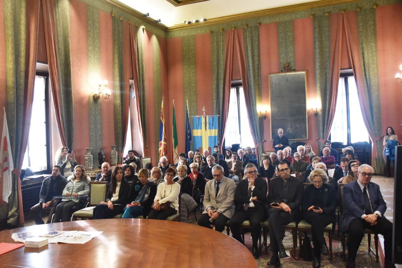 Un gruppo di persone è seduto attorno a un tavolo in una grande stanza.