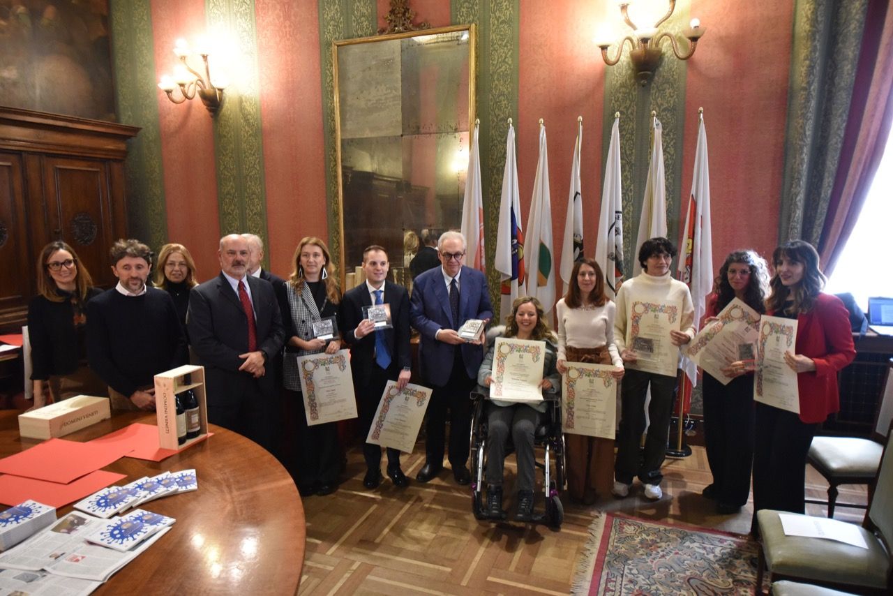 Un gruppo di persone posa per una foto in una stanza con le bandiere.