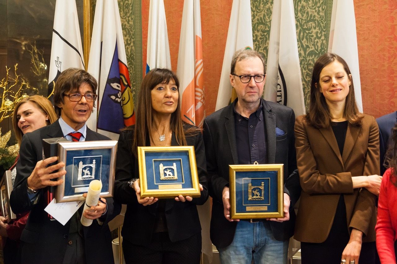 Un gruppo di persone tiene premi davanti alle bandiere