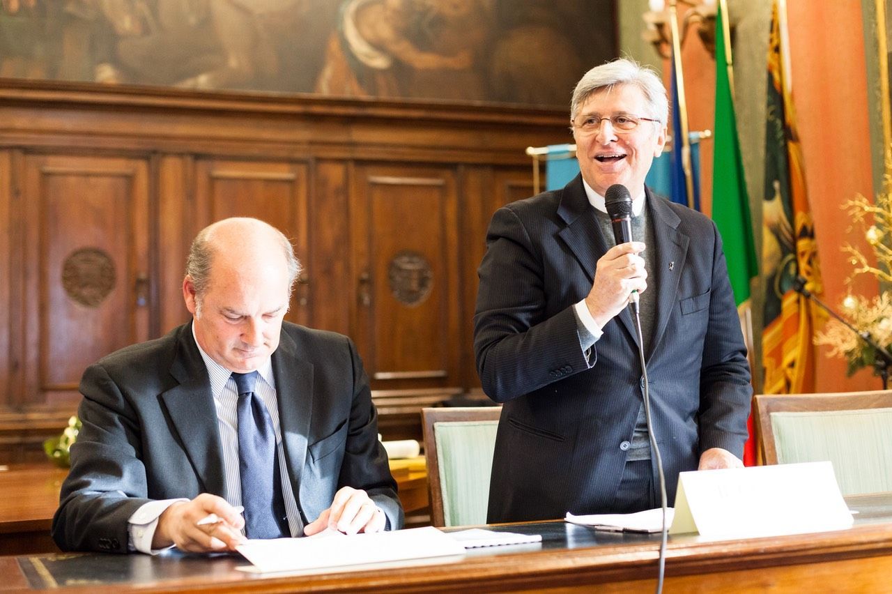 Due uomini sono seduti a un tavolo e uno tiene in mano un microfono