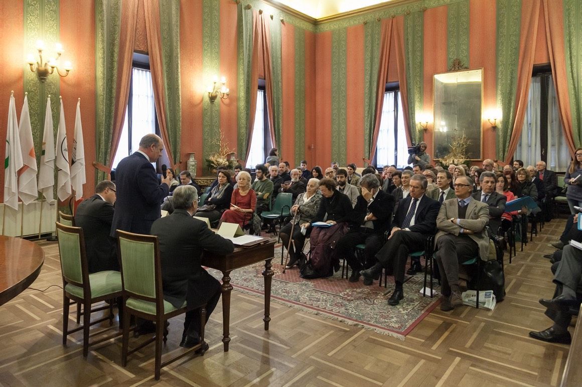 Un gruppo di persone è seduto in una grande stanza.