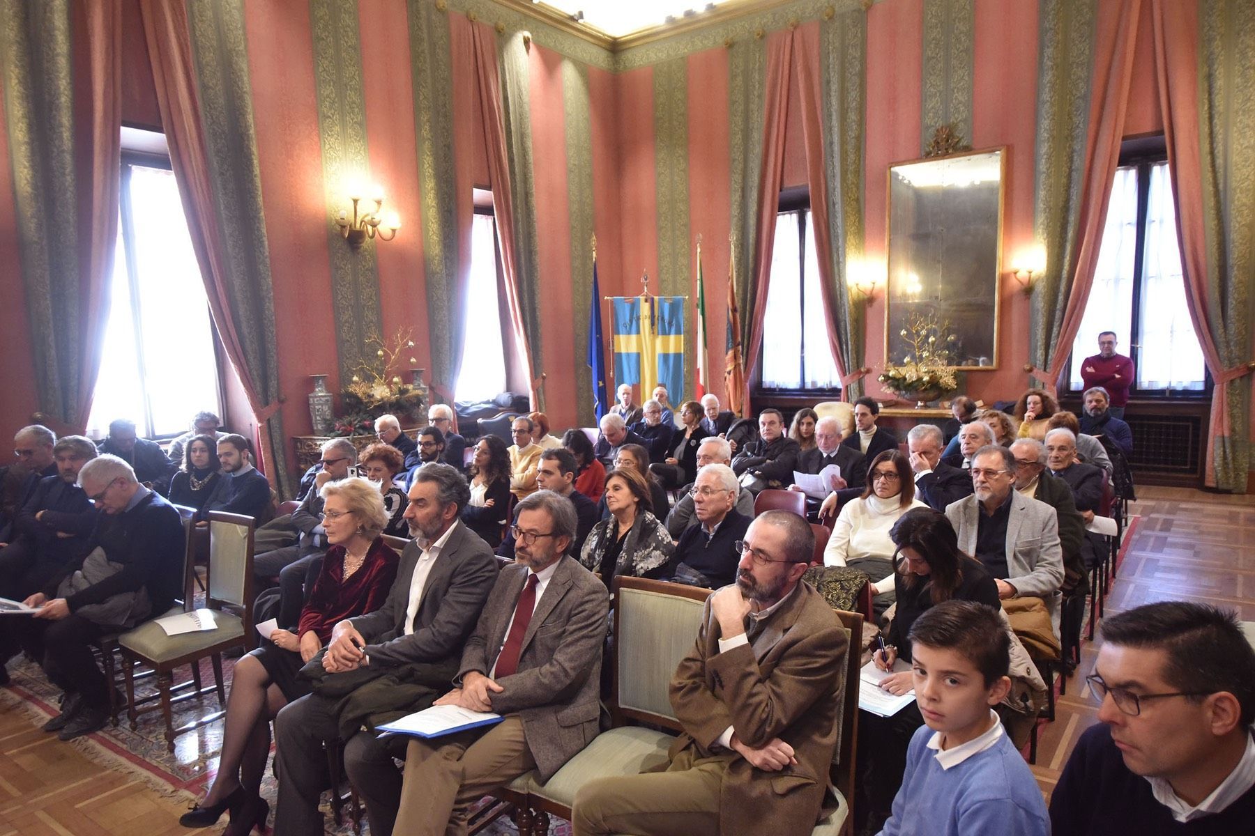 Un folto gruppo di persone è seduto in una grande stanza.