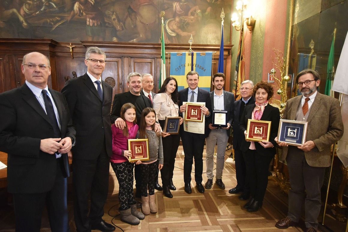 Un gruppo di persone è in piedi in una stanza con in mano delle targhe.