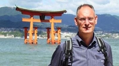 Un uomo è in piedi davanti a un cancello torii in giappone.