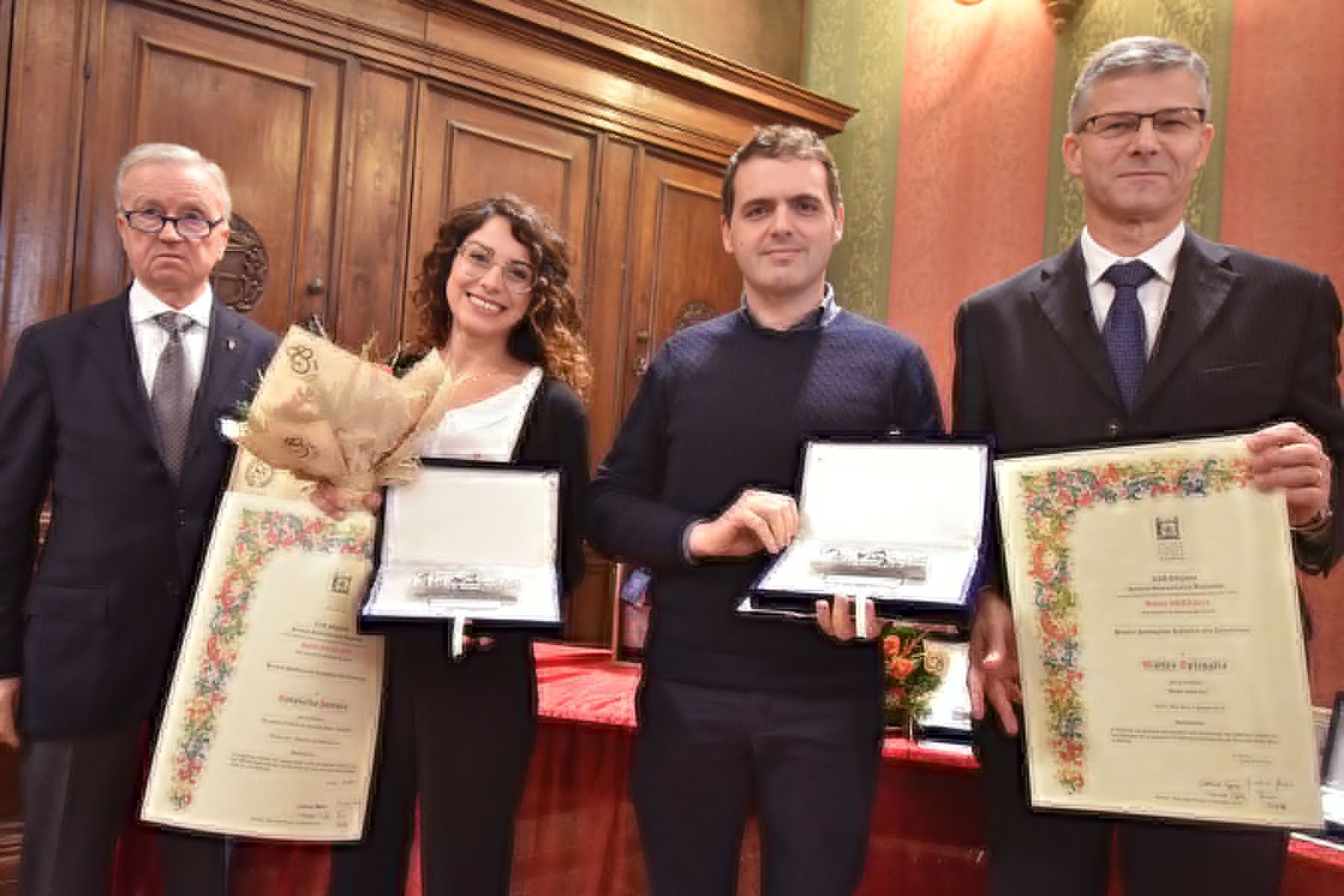 Un gruppo di persone è in piedi uno accanto all'altro con in mano dei premi.