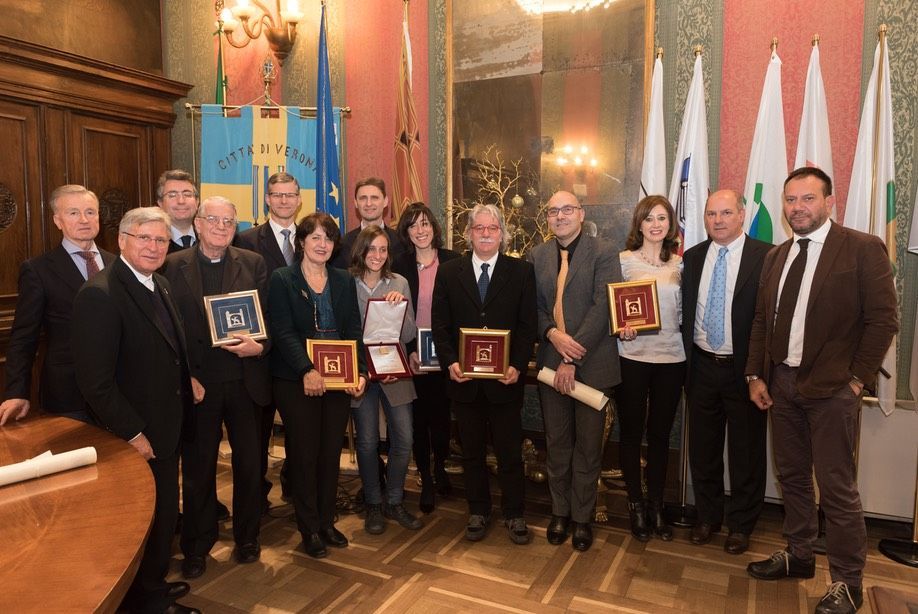 Un gruppo di persone posa per una foto in una stanza con le bandiere.