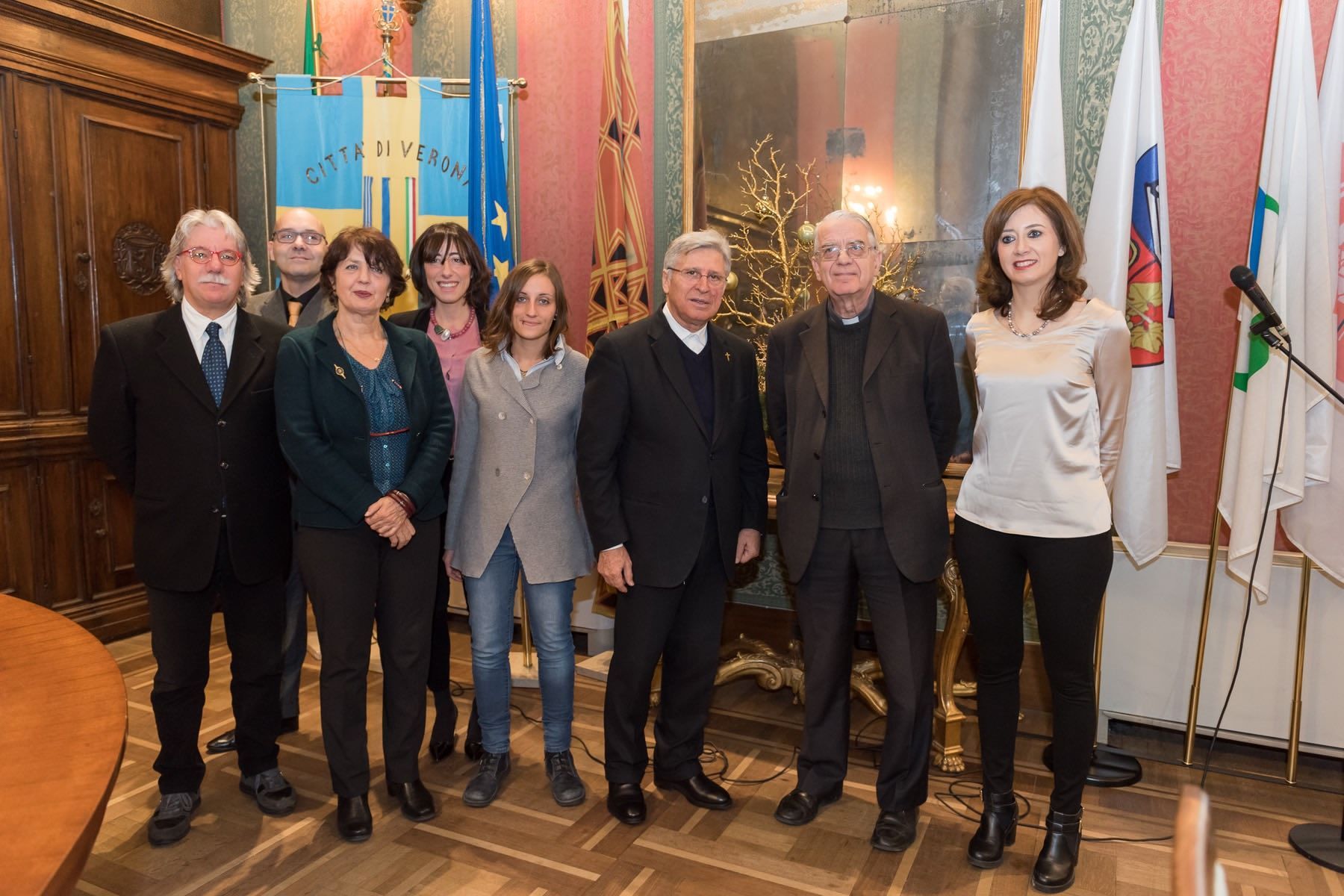Un gruppo di persone posa per una foto in una stanza con le bandiere.