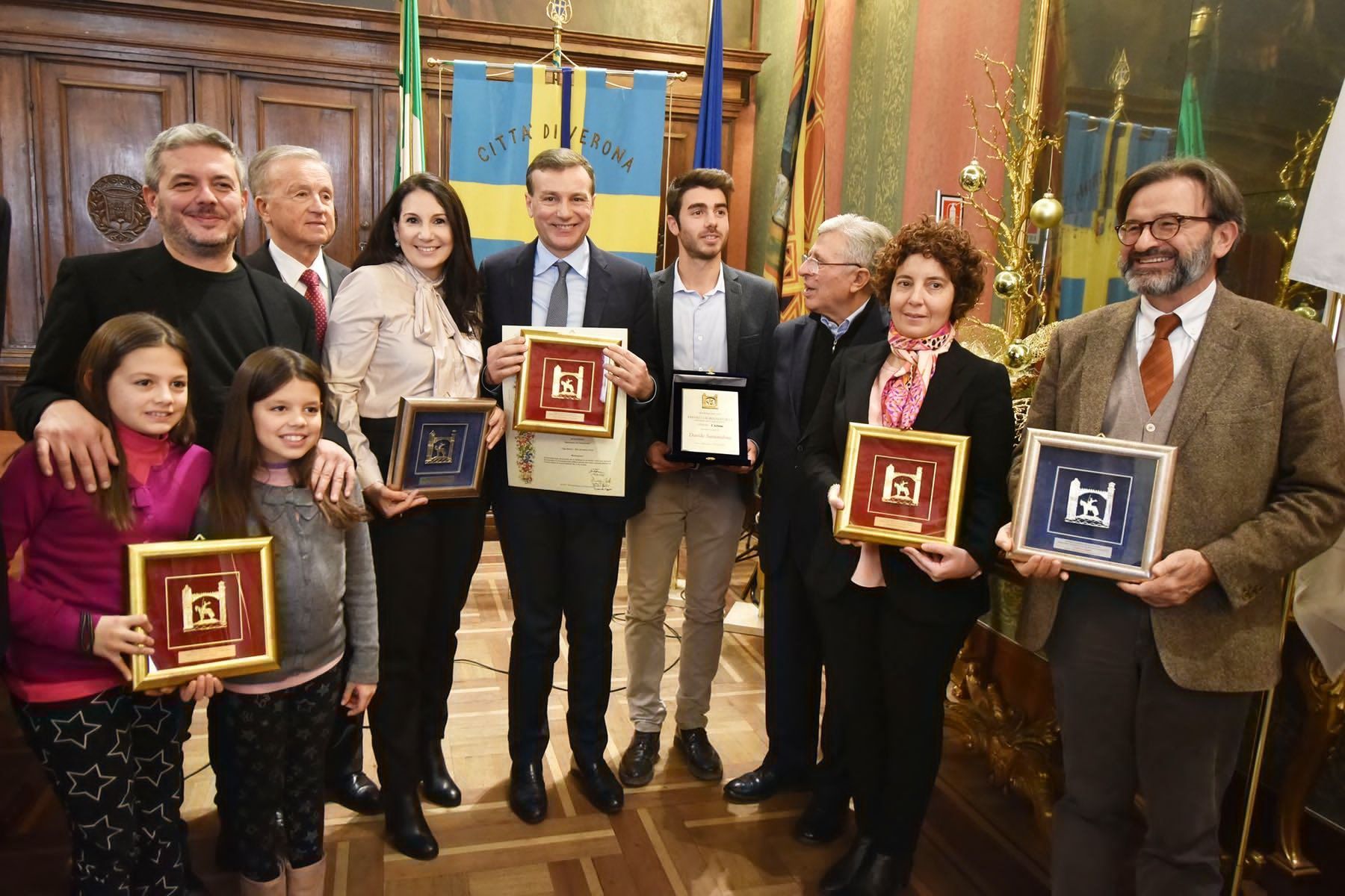 Un gruppo di persone posa per una foto mentre tiene in mano delle targhe.