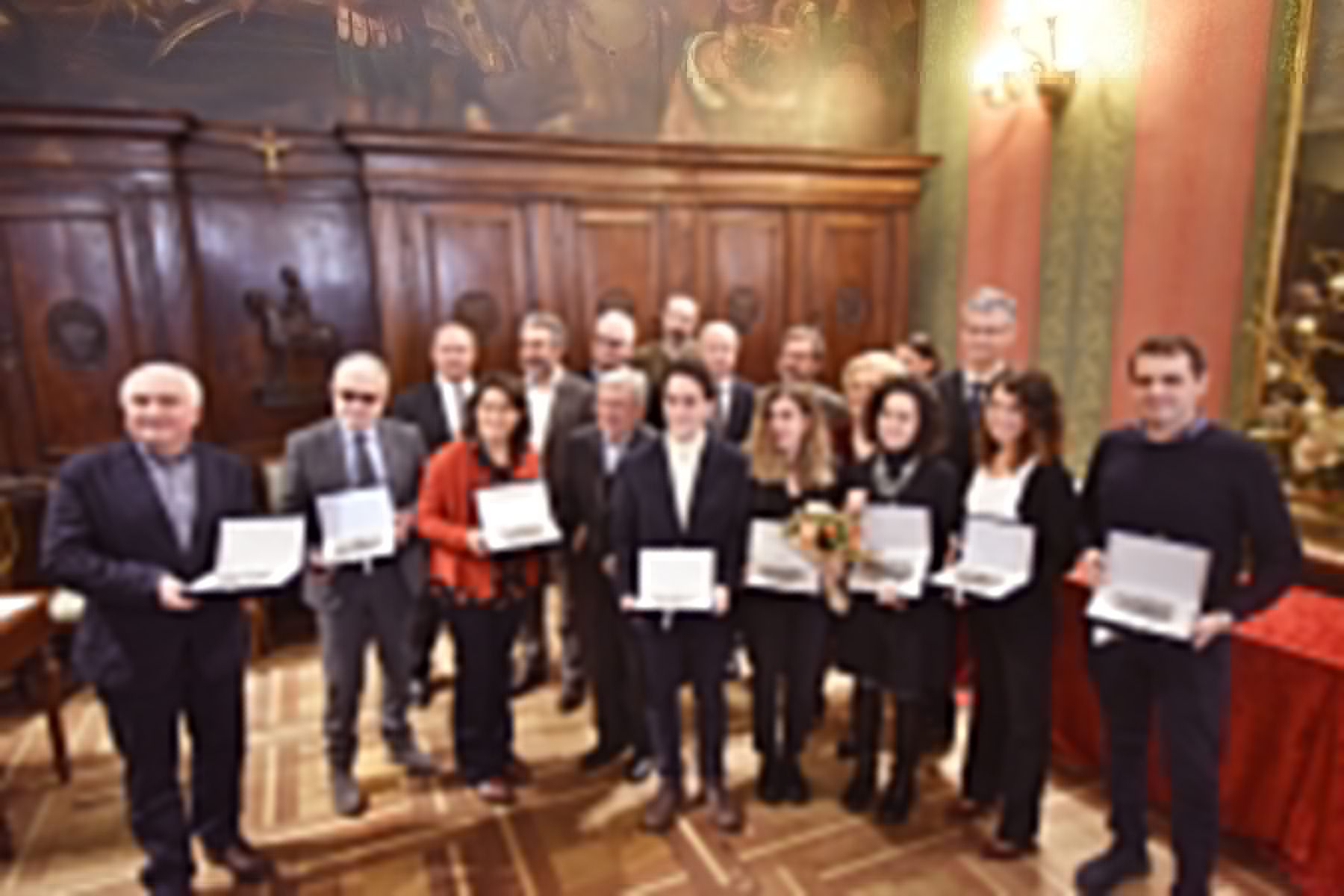 Un gruppo di persone è in una stanza con in mano dei premi.