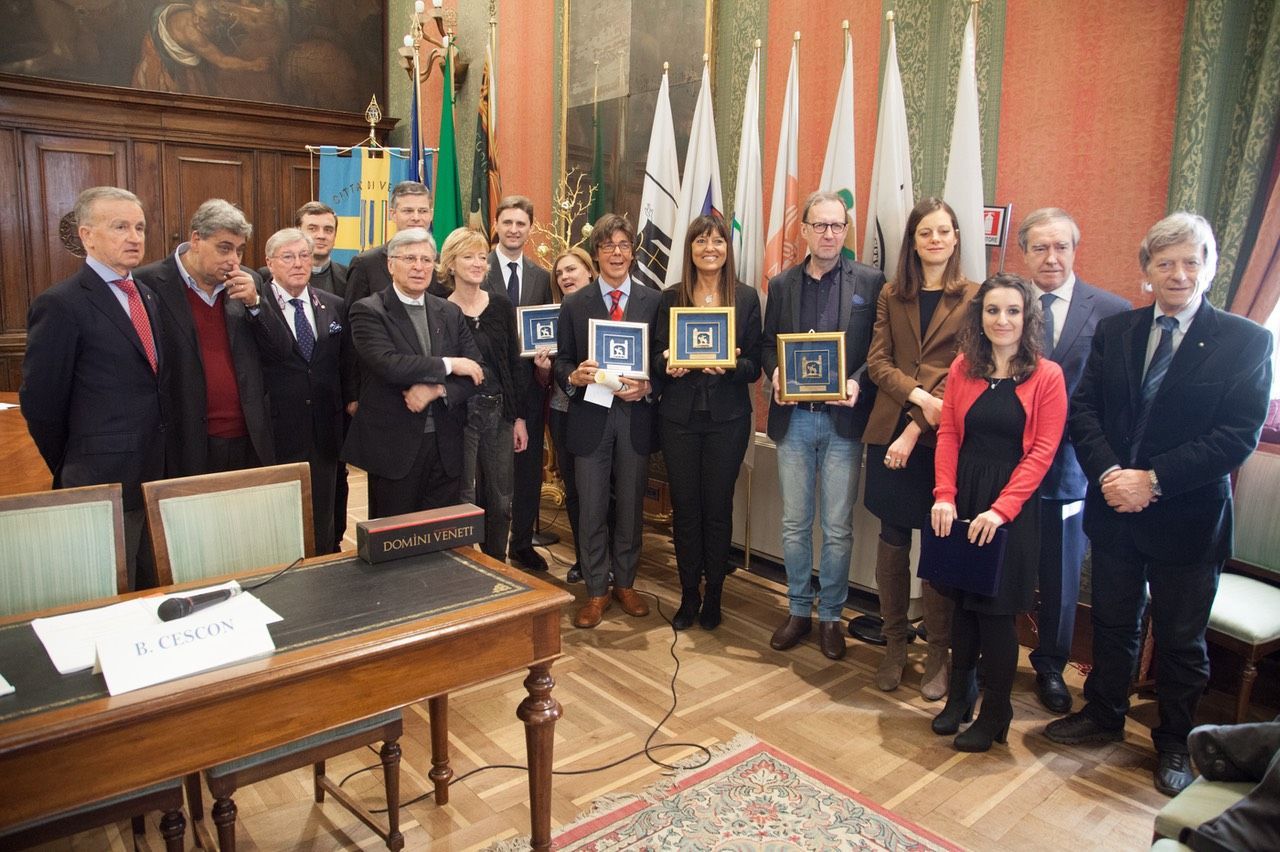 Un gruppo di persone posa per una foto in una stanza con le bandiere.