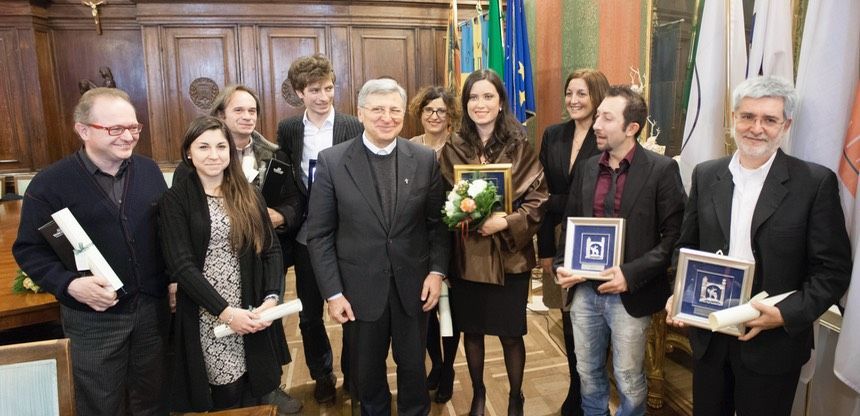 Un gruppo di persone in piedi una accanto all'altra con in mano delle targhe.