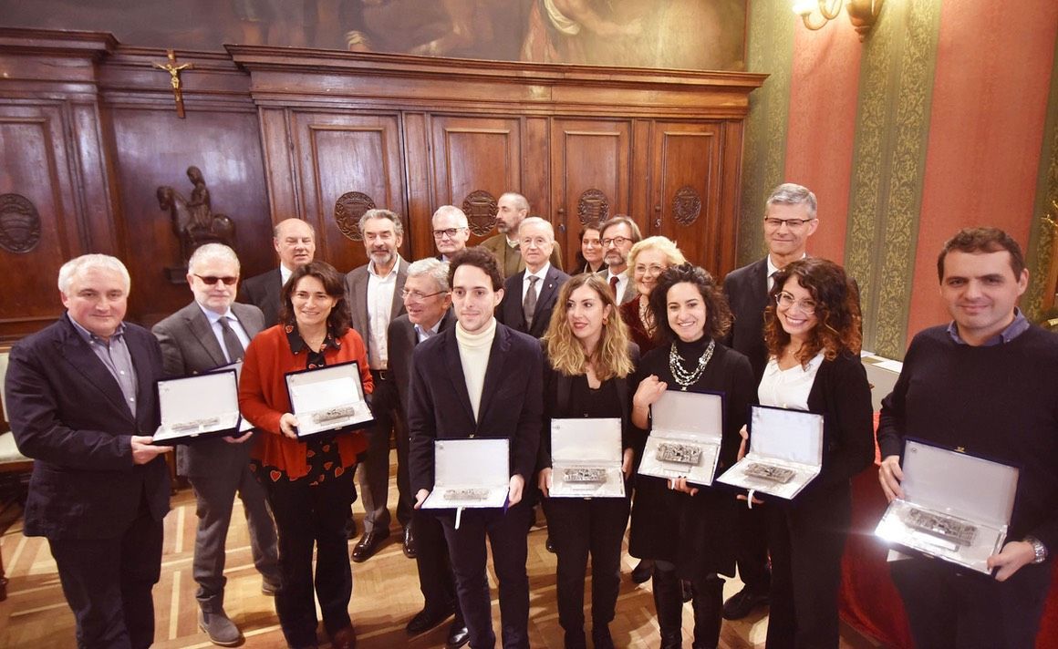Un gruppo di persone è in piedi in una stanza con in mano delle targhe.