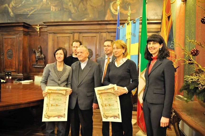 Un gruppo di persone in piedi in una stanza con in mano delle targhe