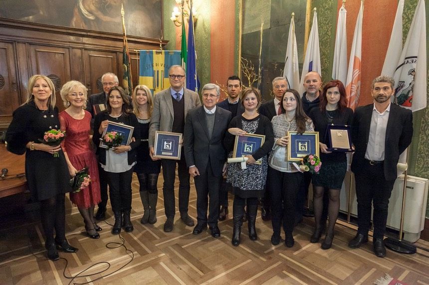 Un gruppo di persone posa per una foto in una stanza con le bandiere.