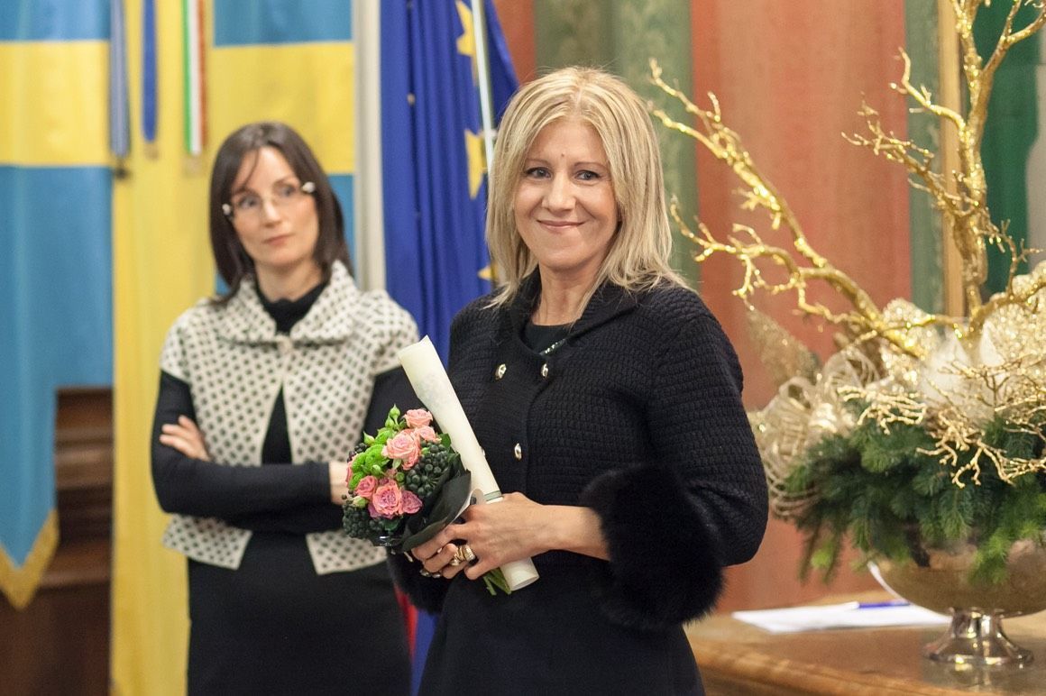 Due donne sono in piedi una accanto all'altra e una tiene in mano un mazzo di fiori