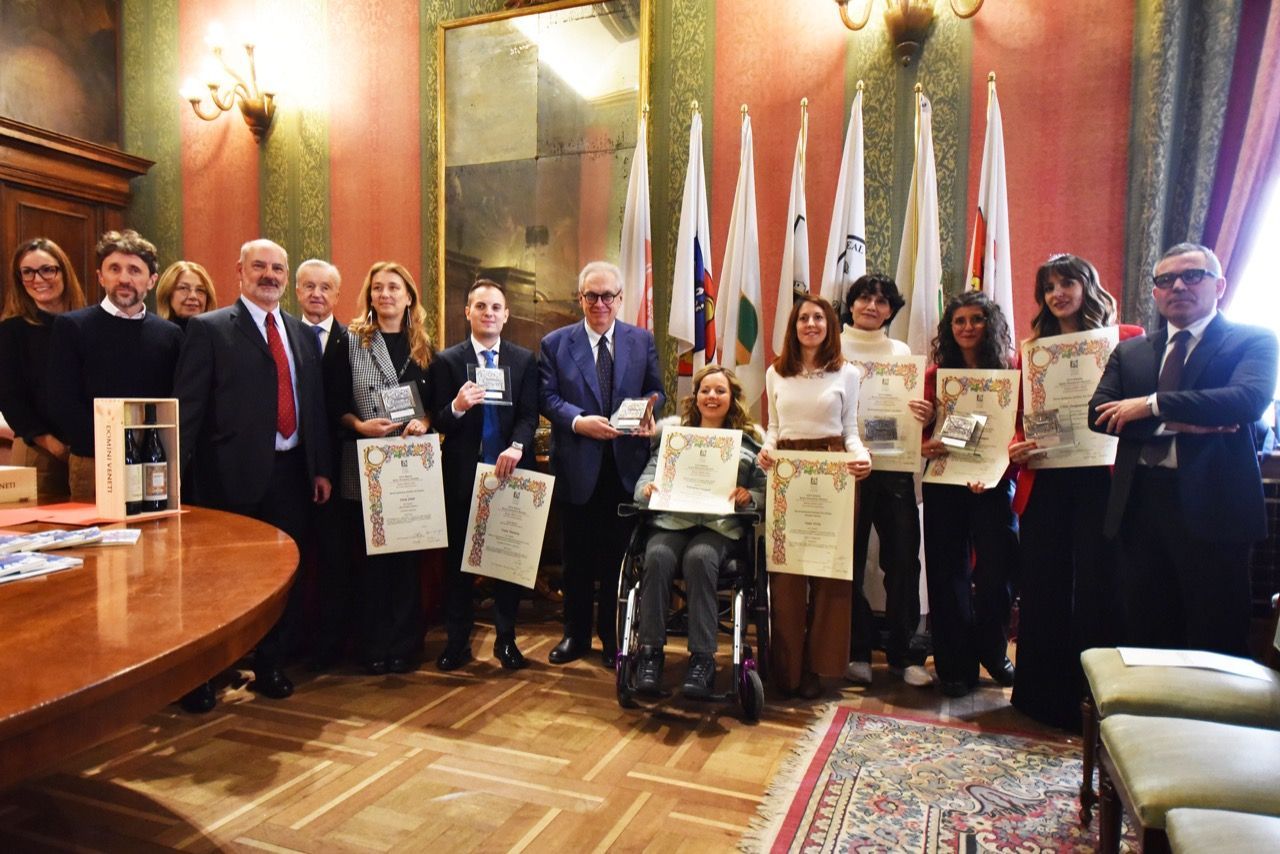 Un gruppo di persone posa per una foto in una stanza con le bandiere.