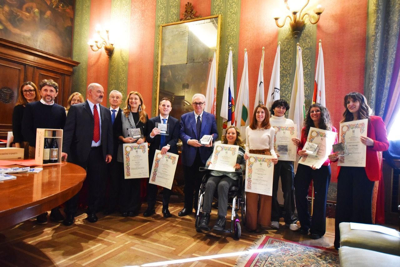 Un gruppo di persone posa per una foto in una stanza con le bandiere.