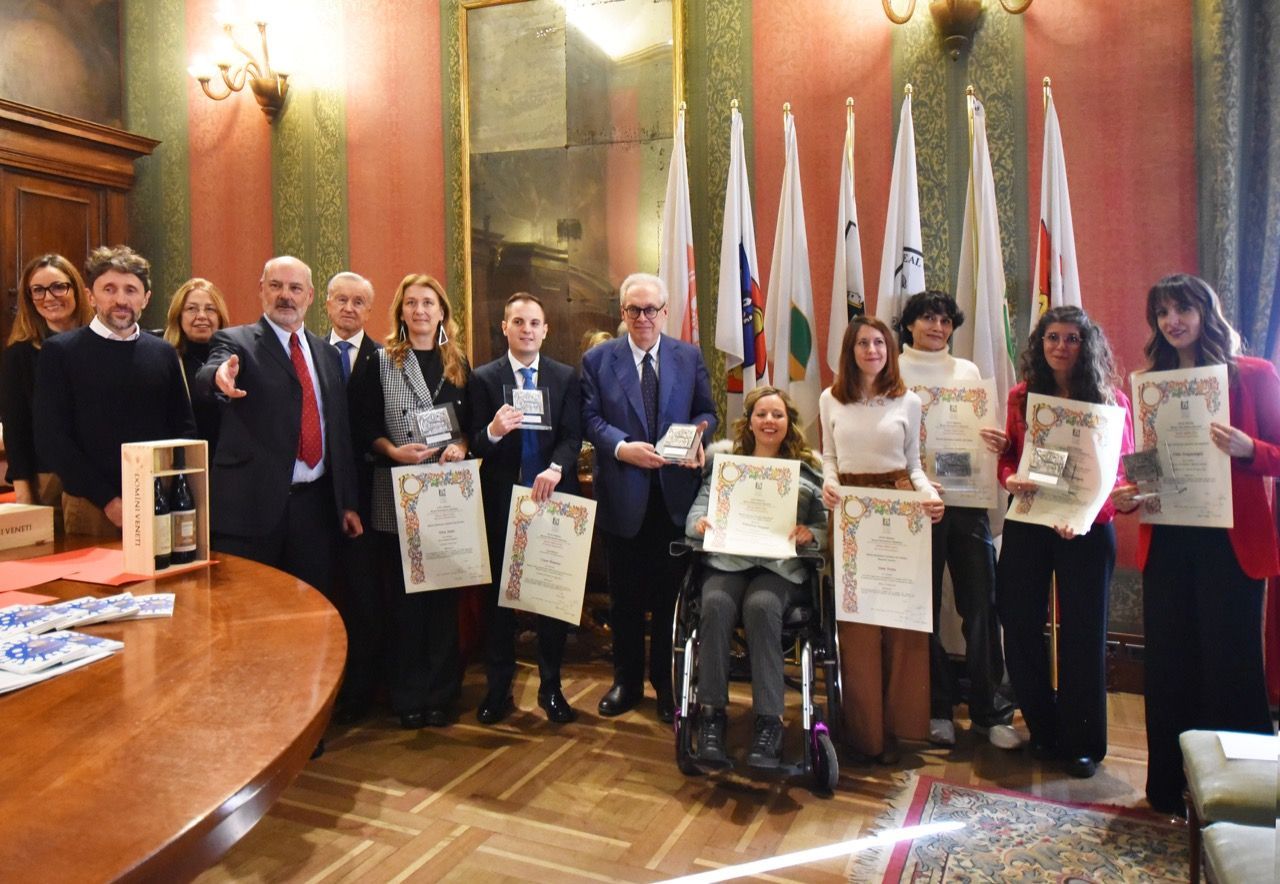 Un gruppo di persone posa per una foto in una stanza con le bandiere.