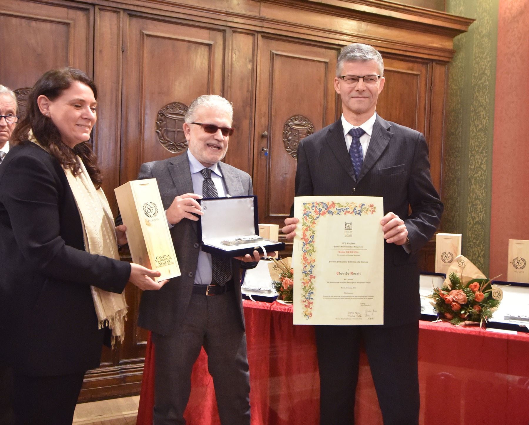 Un gruppo di persone è in piedi attorno a un tavolo con in mano un certificato.