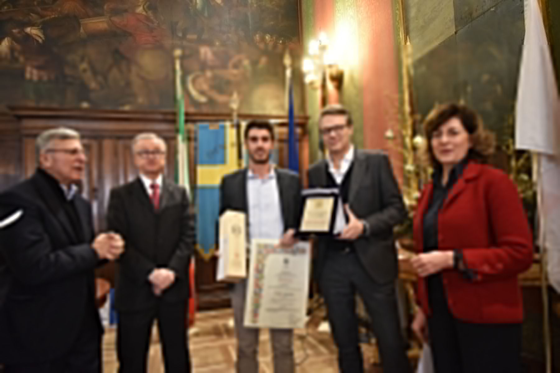 Un gruppo di persone sono in piedi una accanto all'altra in una stanza con in mano delle targhe.