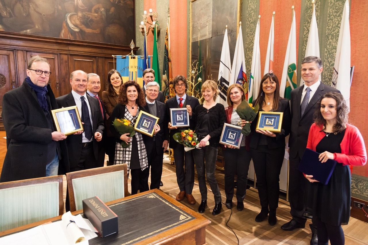 Un gruppo di persone posa per una foto in una stanza con le bandiere.