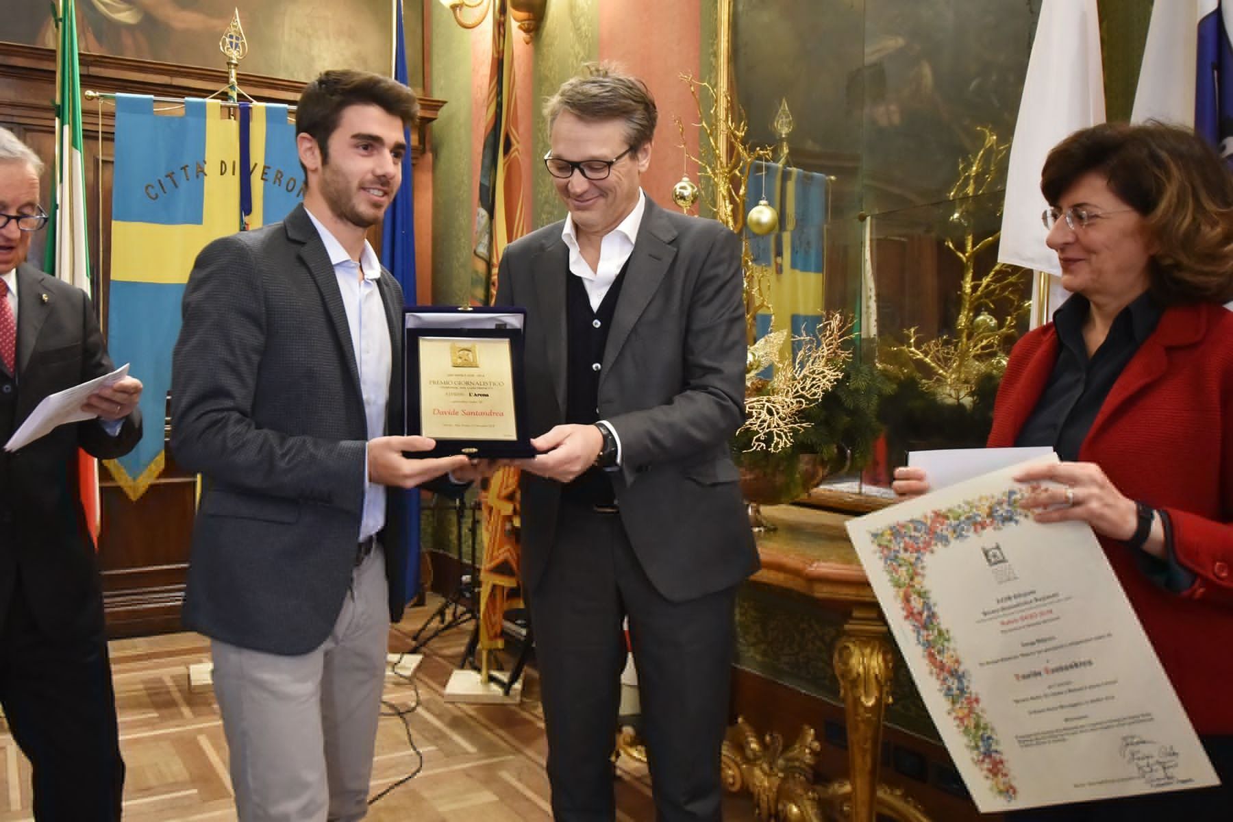 Un uomo tiene in mano una targa e una donna tiene in mano un certificato.