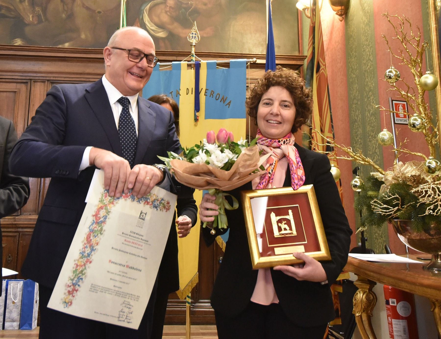 Un uomo e una donna tengono in mano un certificato e un mazzo di fiori