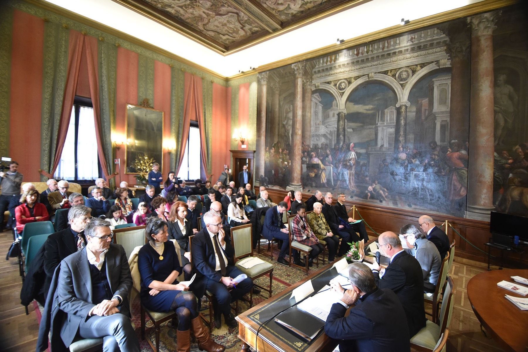 Un gruppo di persone è seduto in una grande stanza.