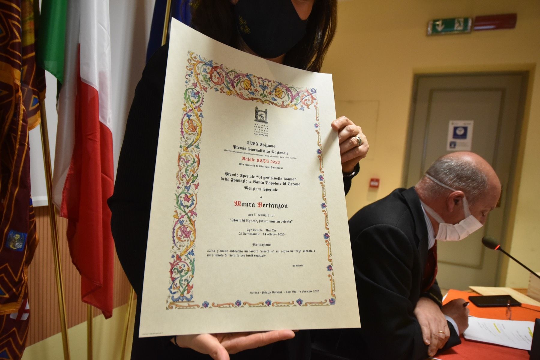 Una donna che indossa una maschera ha in mano un certificato