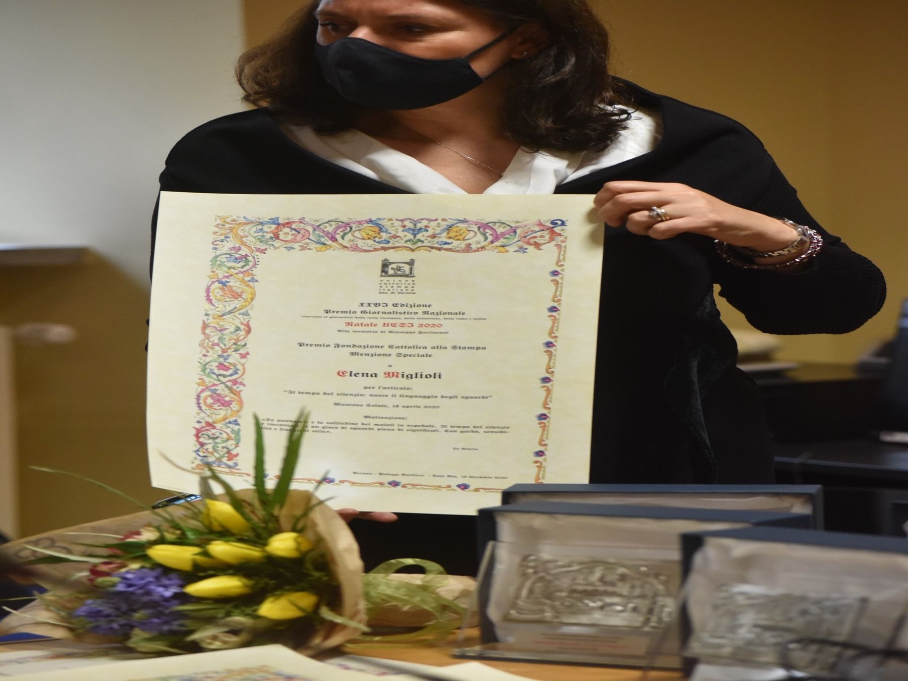 Una donna che indossa una maschera ha in mano un certificato