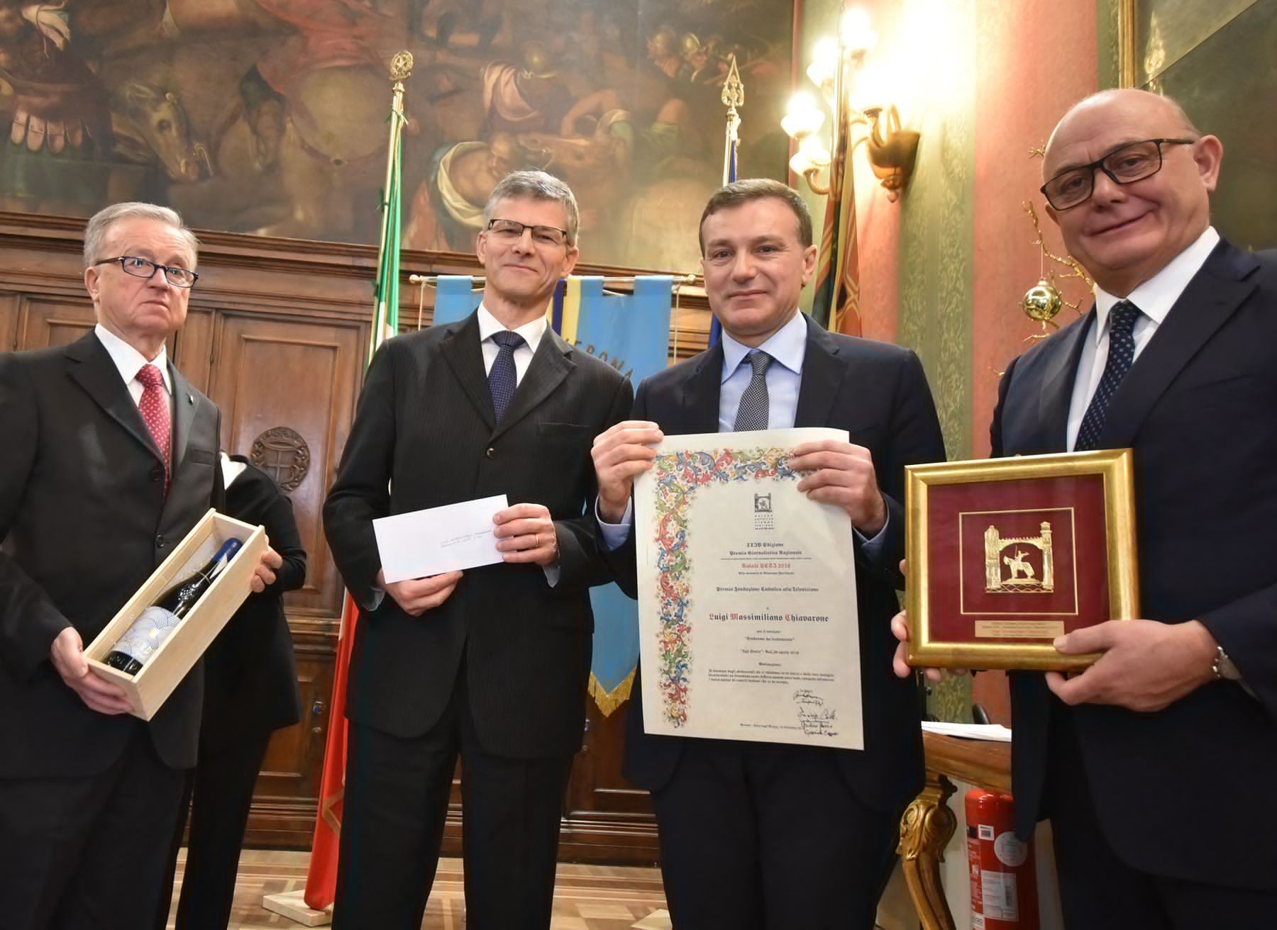Un gruppo di uomini in giacca e cravatta tengono in mano dei premi