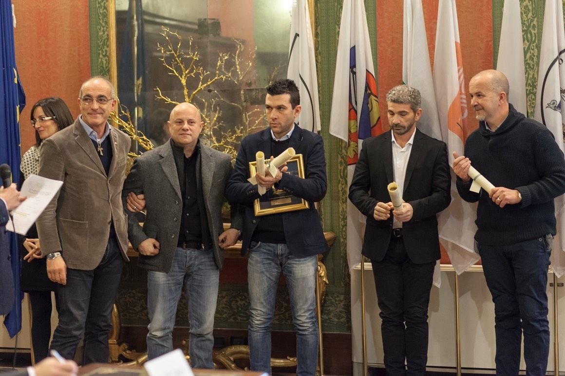Un gruppo di uomini sta uno accanto all'altro davanti alle bandiere.