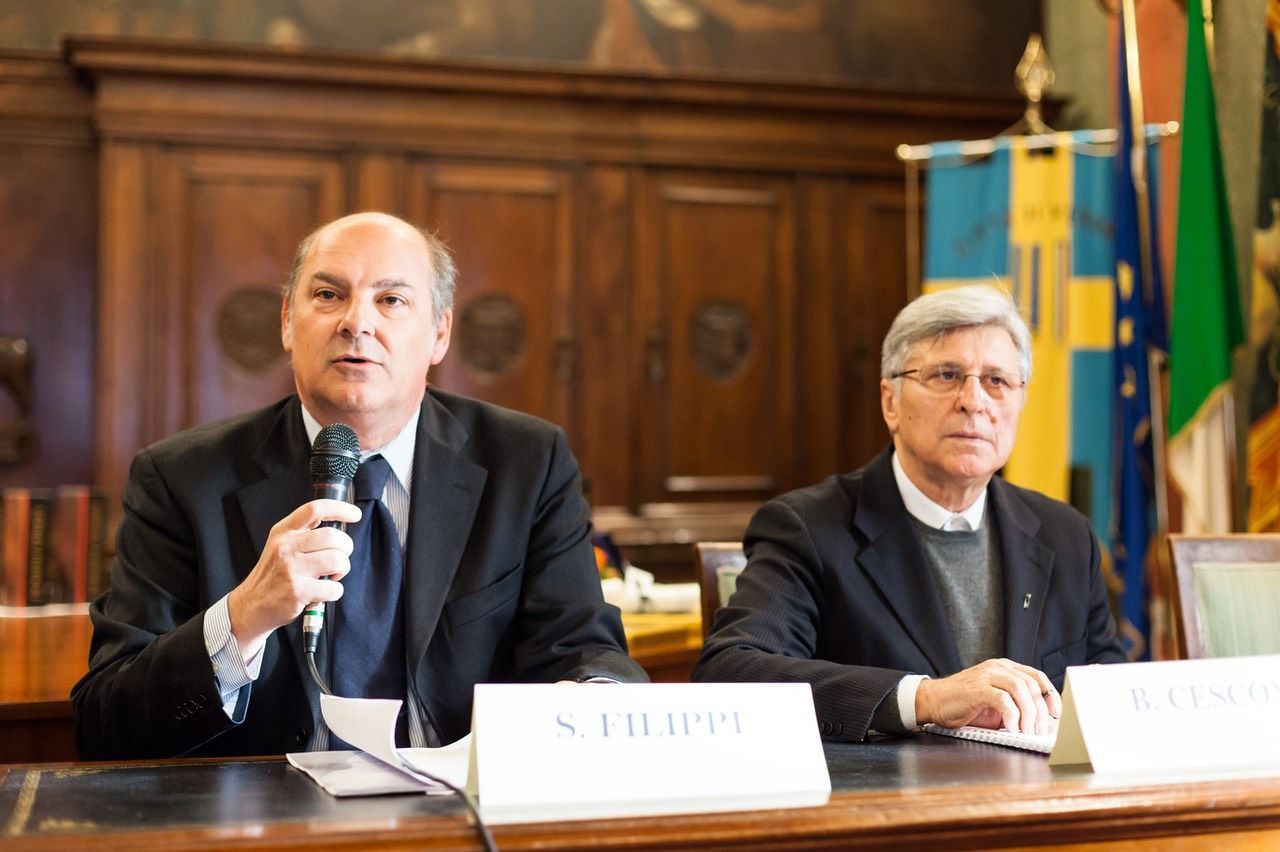 Due uomini sono seduti a un tavolo e uno tiene in mano un microfono.