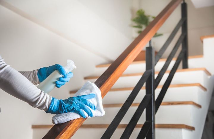 a worker cleaning the handles near the stairs