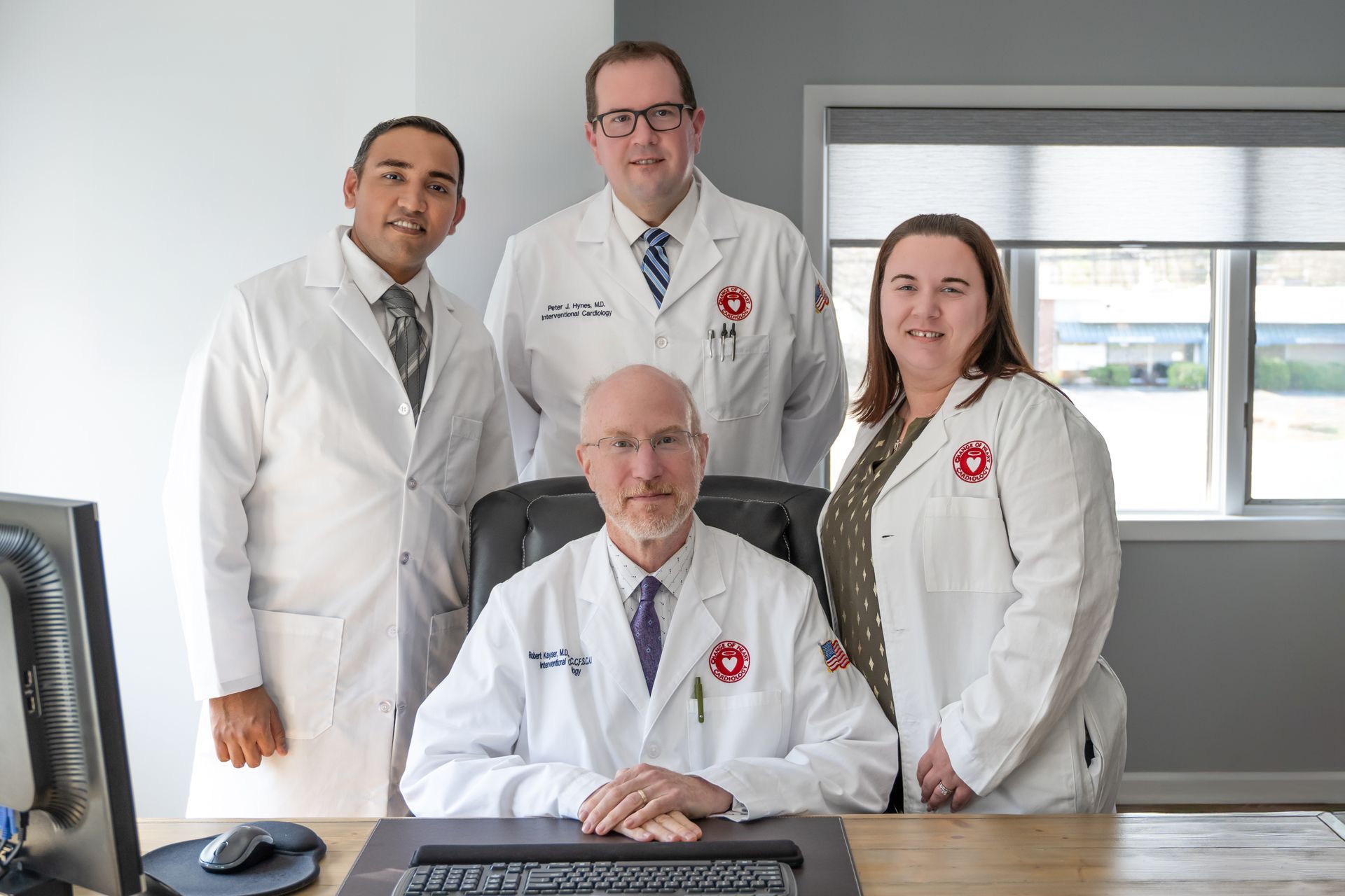Four medical professionals in white coats pose in an office.