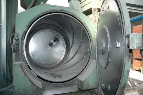 Camera industriale aperta con grande porta metallica circolare e tamburo all'interno di un ambiente di fabbrica
