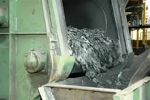 Rottami metallici che cadono da un macchinario industriale in un contenitore di raccolta.