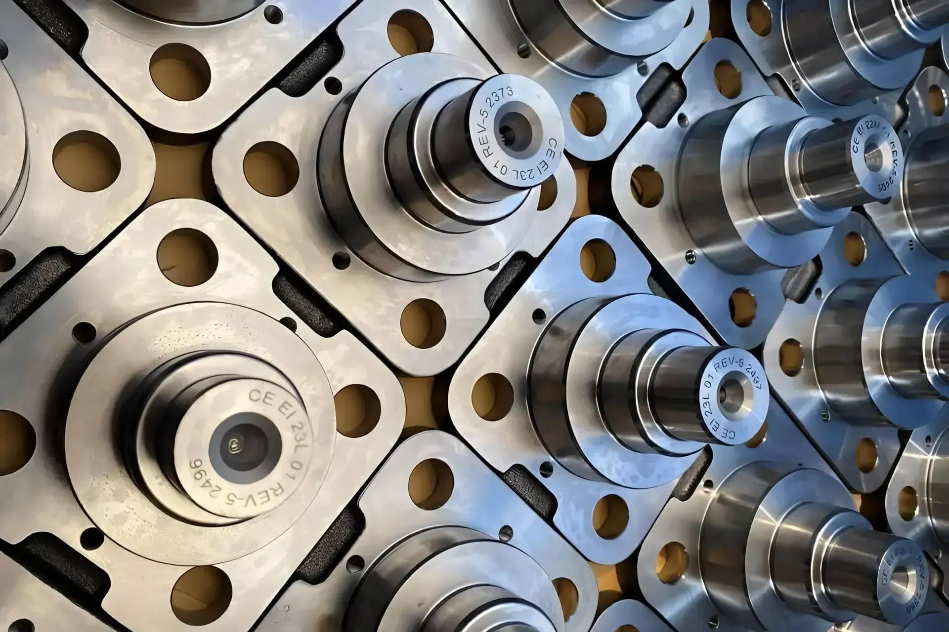 Primo piano di componenti meccanici in metallo lucido e di elementi circolari di precisione disposti secondo uno schema ripetitivo.