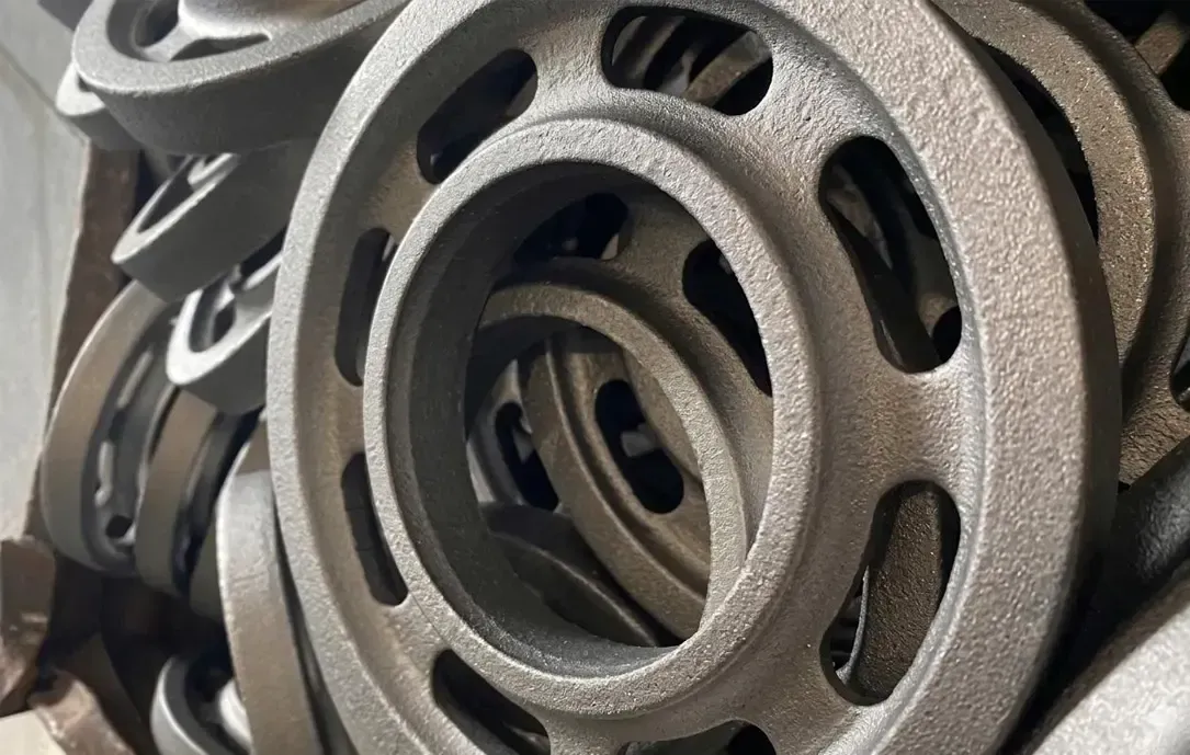 Immagini ravvicinate di pulegge metalliche impilate con intagli ovali in un contesto industriale.