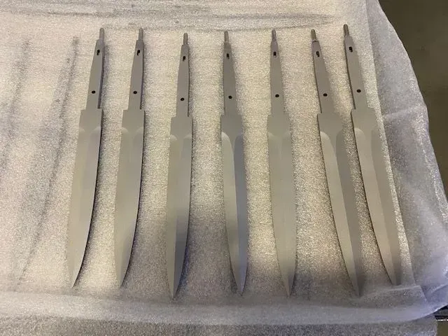 Sei mollette metalliche argentate disposte ordinatamente su una superficie di tessuto bianco