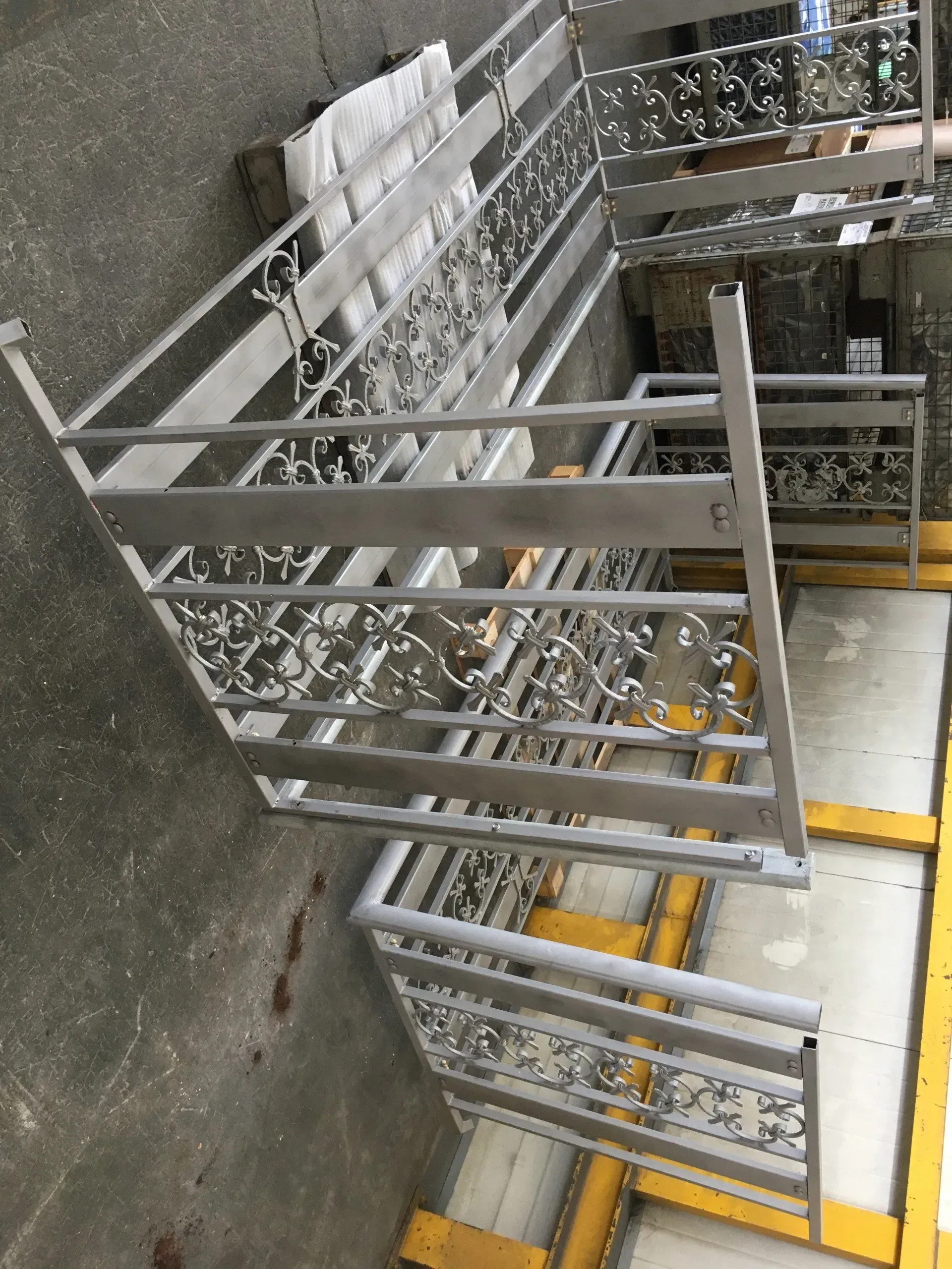 Scaffale metallico con vassoi impilati in un'area di stoccaggio accanto a un passaggio a strisce gialle.