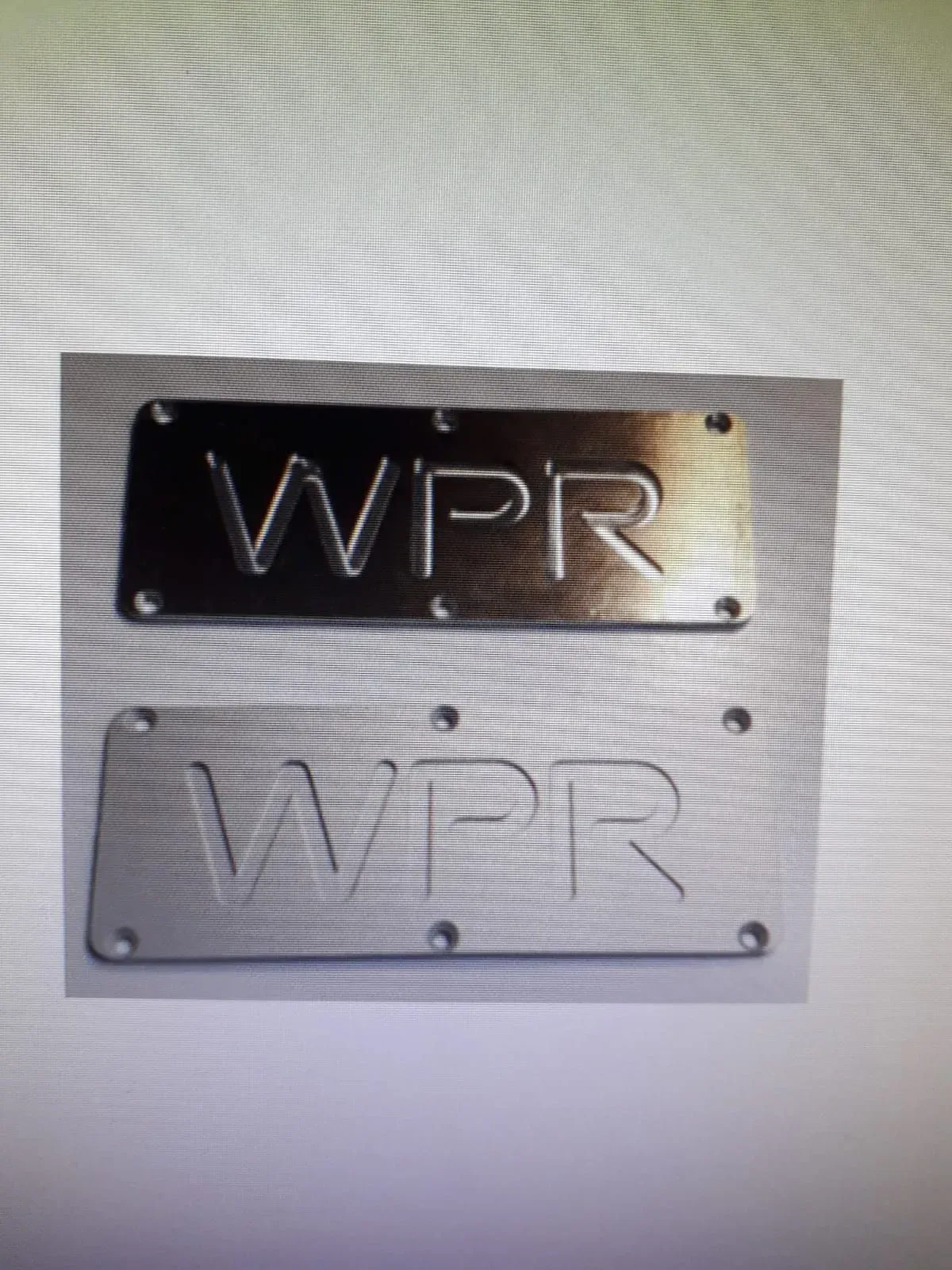 Due targhe metalliche con incisa la scritta “WPR”, una scura e una argentata, montate a parete.