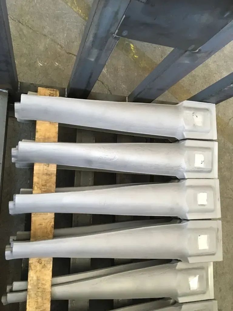 Cinque componenti in plastica bianca curva impilati su un pallet di legno in un magazzino.