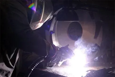 Primo piano di una figura scura e corazzata che si protende verso un'esplosione di energia viola brillante.