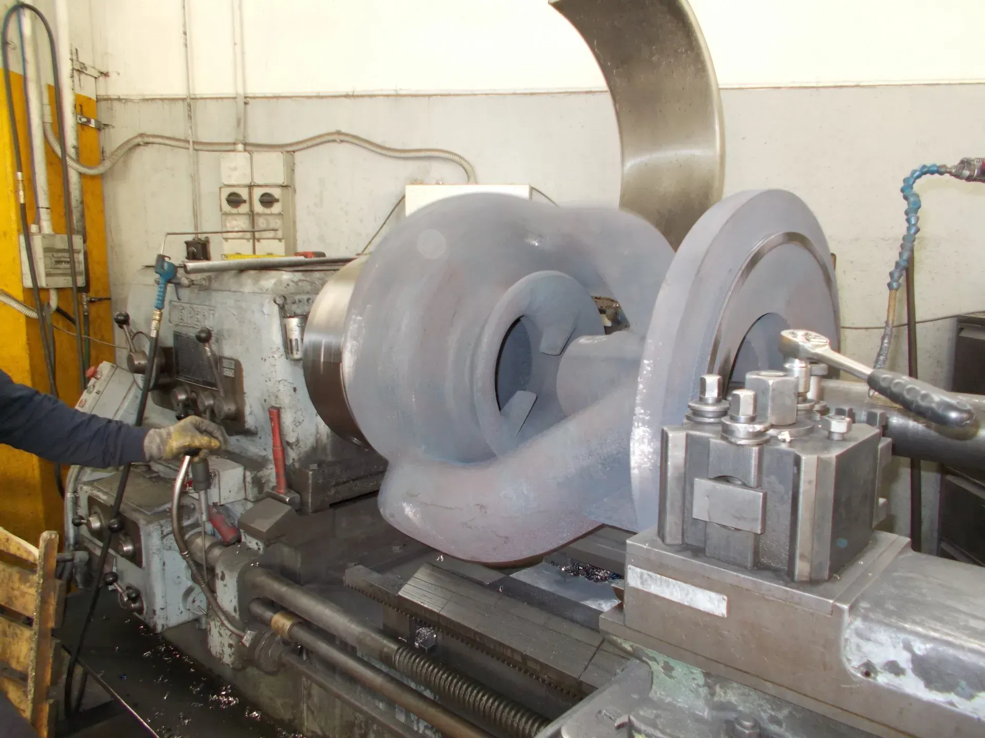 Macchina industriale con grandi rulli metallici che modella una lamiera curva in un'officina