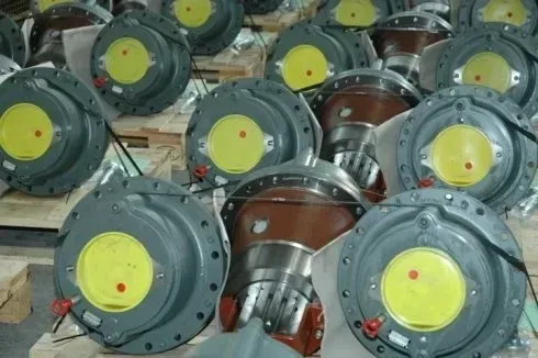 Assemblaggi di valvole metalliche industriali impilate con centri gialli sul pavimento di un magazzino.