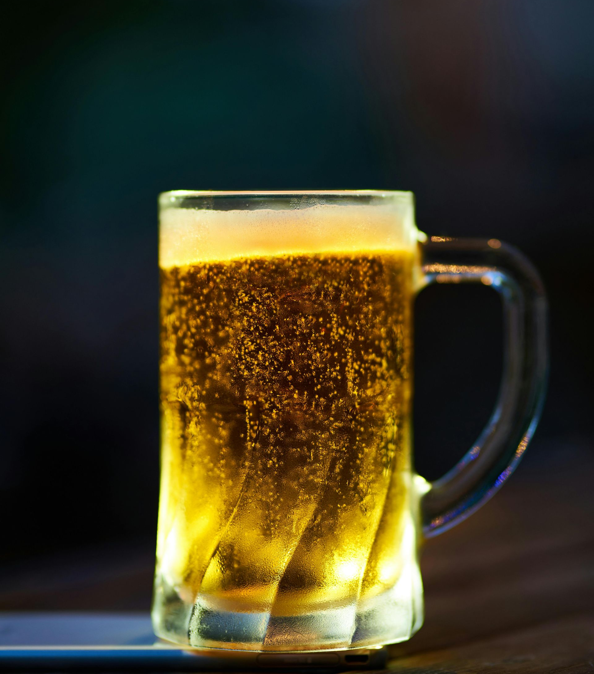 A glass beer mug filled with golden beer, bubbles, and foam.