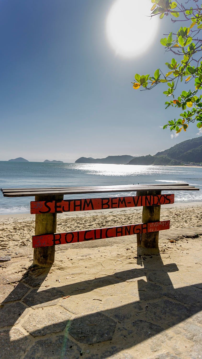 Um banco de madeira na praia com uma placa que diz bem-vindo