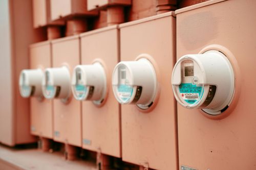 Row of white utility meters mounted on a peach-colored wall