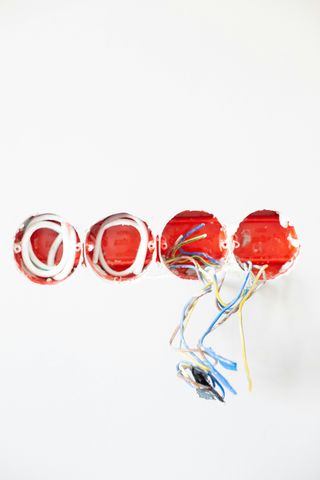 Red electrical relay with dangling multicolored wires on a white background